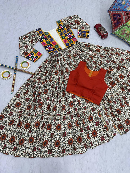Flat lay of Kachchi Charm lehenga choli set with mirror work shrug, orange blouse, and flared skirt.