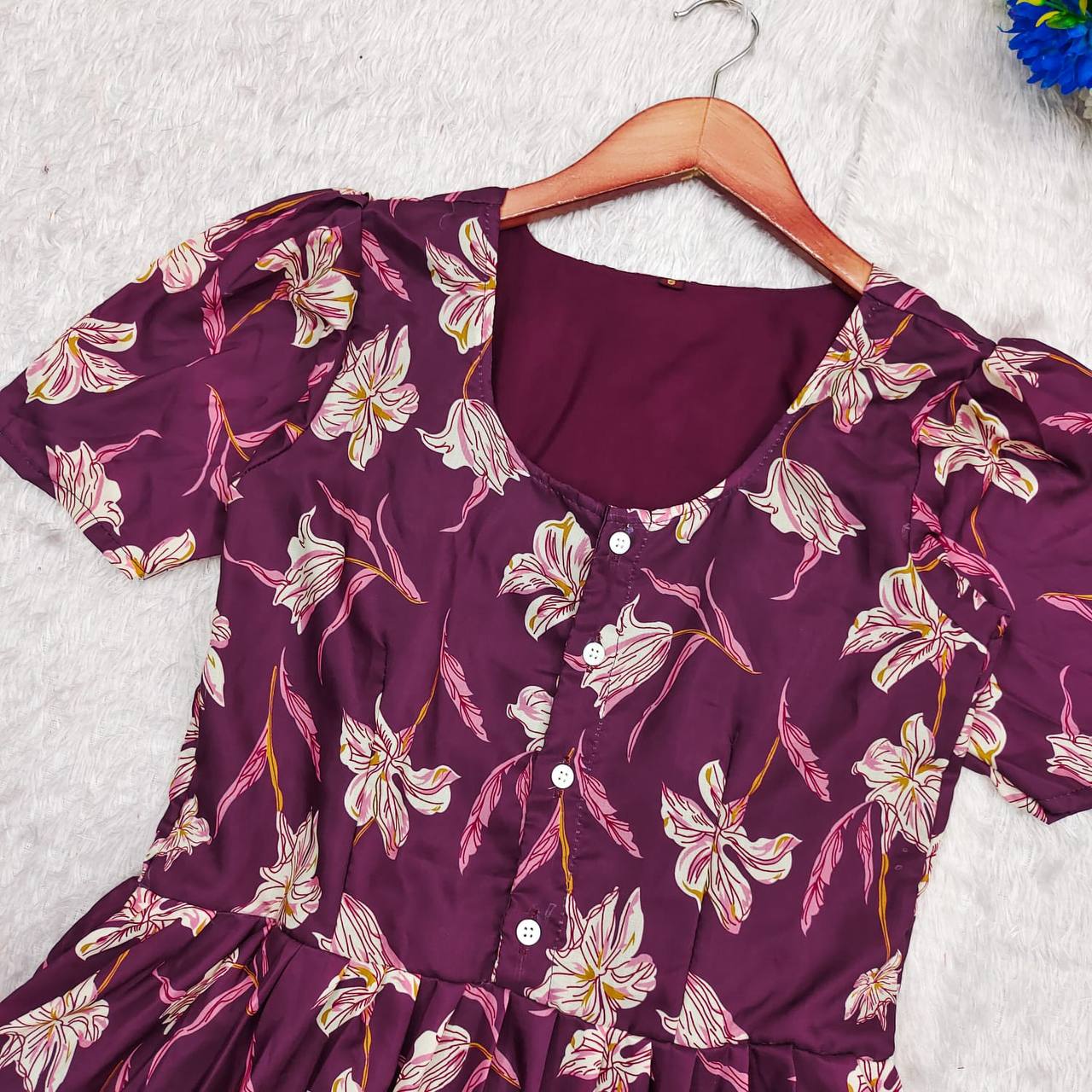 Close-up of the Moringa Maxi dress showing the neckline, buttons, and floral pattern in plum.
