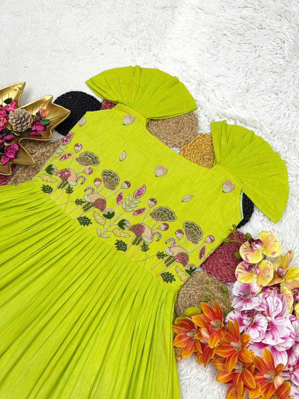 Detailed view of the green and blue cotton gown with handwork, surrounded by floral decor.