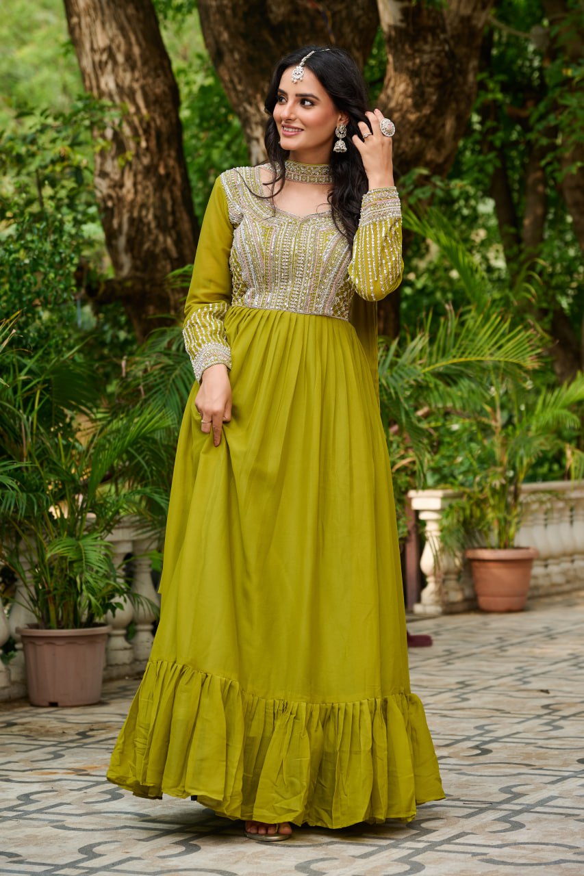 Woman in a green dress standing outdoors with trees and plants in the background