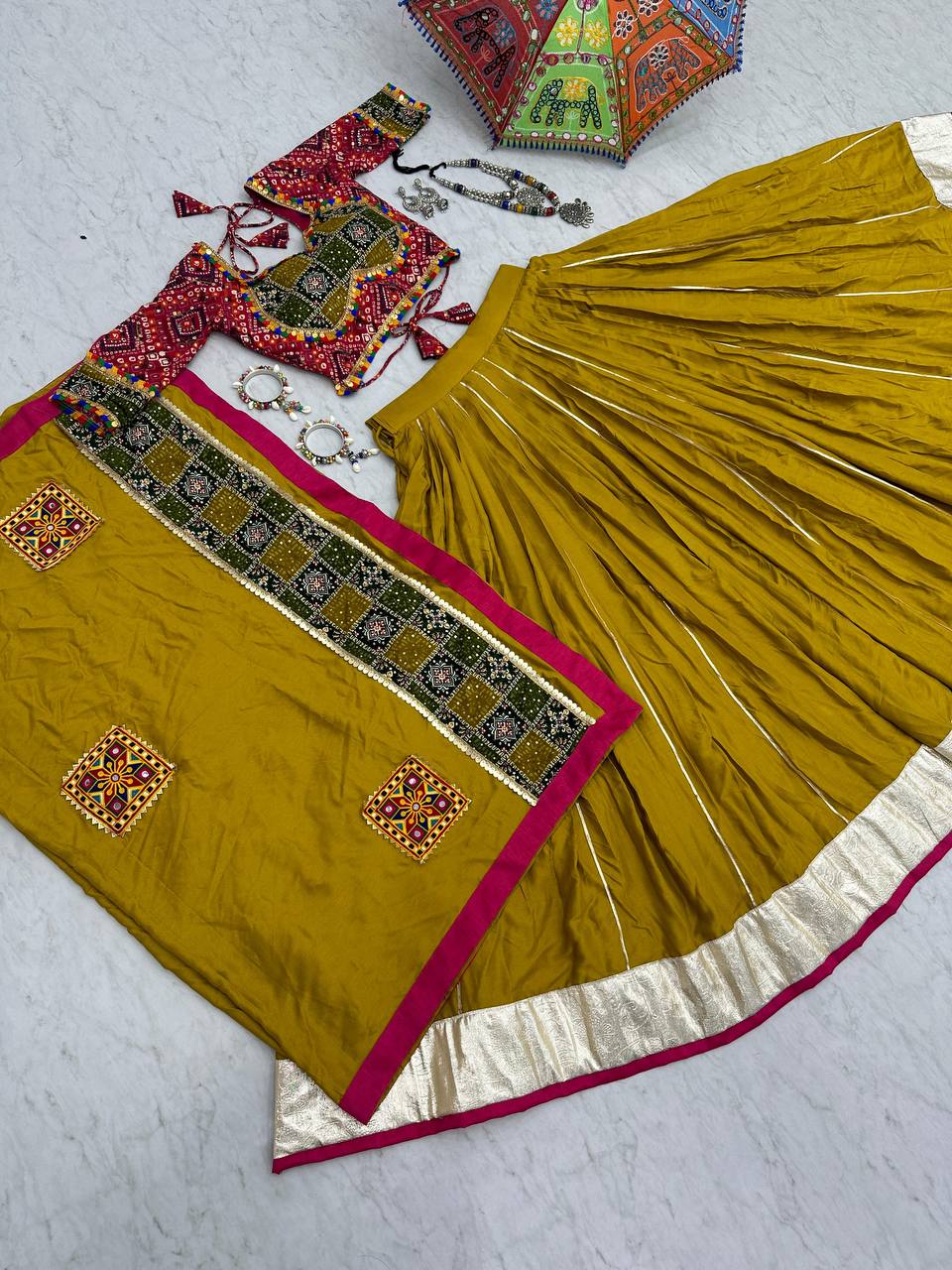 Golden yellow Navratri lehenga, choli, and dupatta flat lay with silver and beaded jewelry.