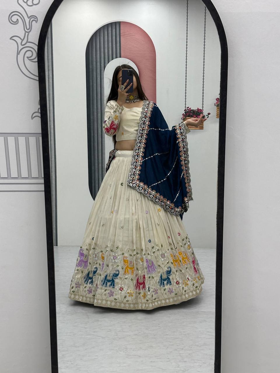 Full mirror view of an off-white lehenga choli with elephant design and a navy blue dupatta.