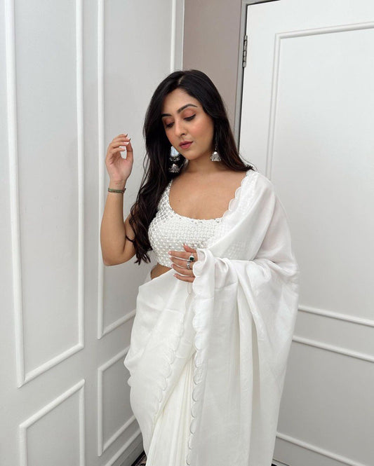 Woman wearing elegant white Rangoli silk saree with beaded blouse and jhumka earrings.