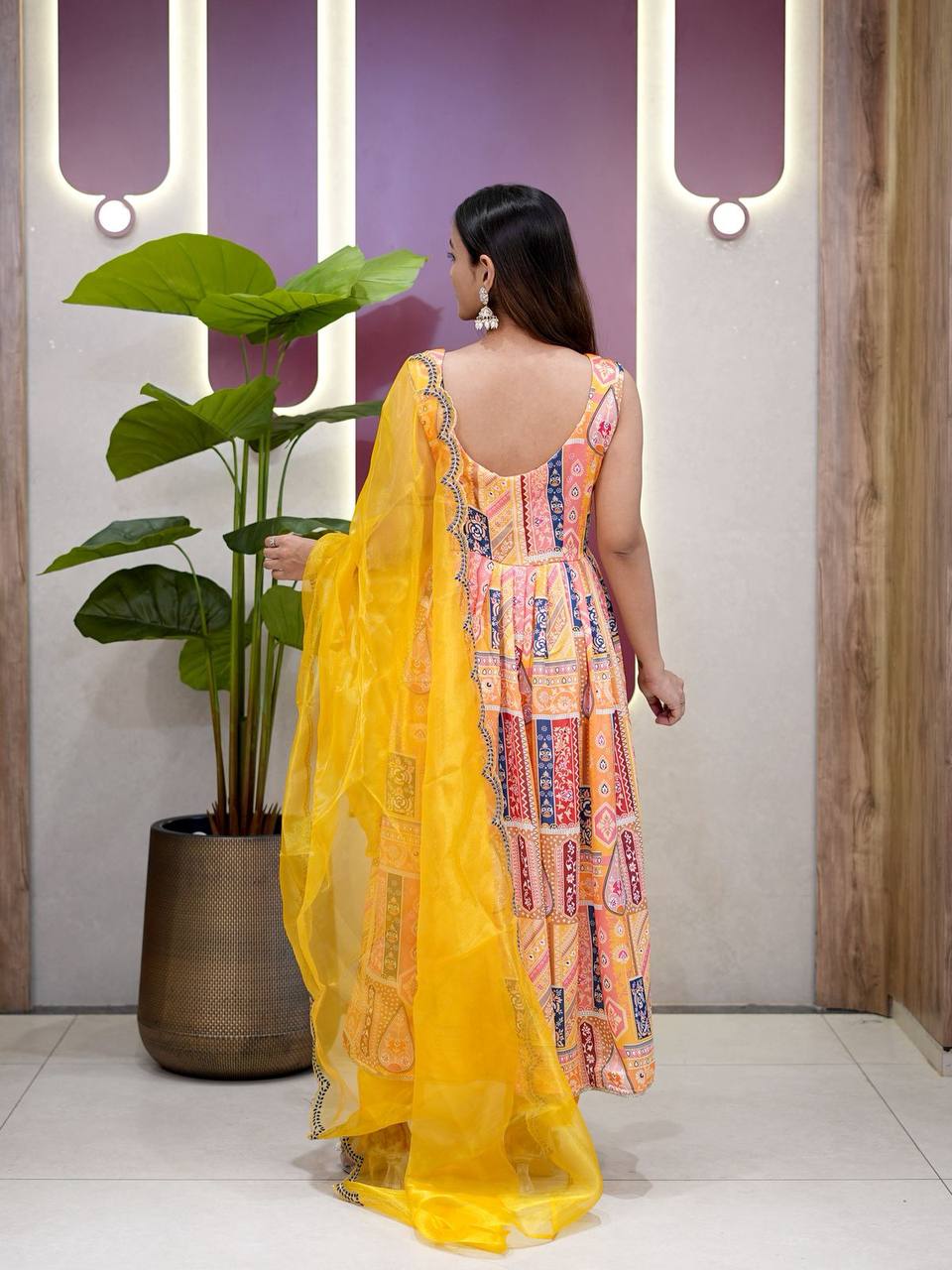 Back view of yellow Anarkali suit showing flared silhouette and dupatta detail.