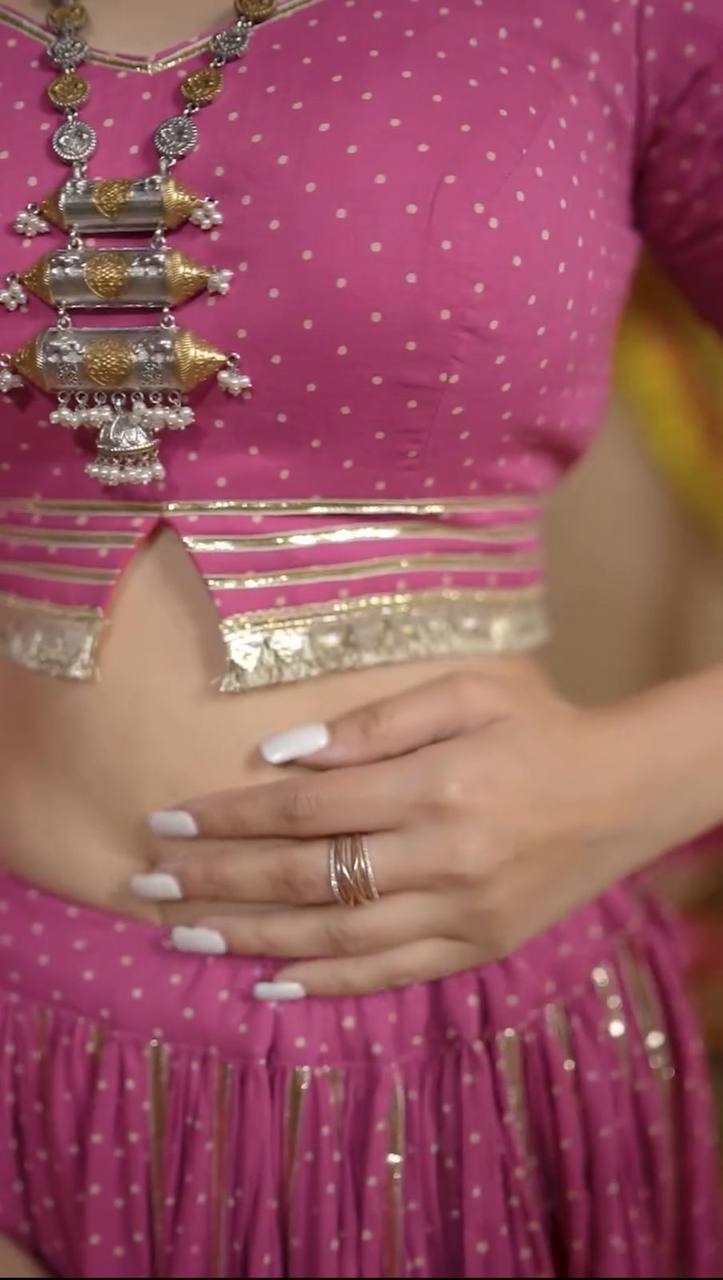 Detailed close-up of pink choli’s metallic ribbon border and polka dots, showing ring and manicured hand.