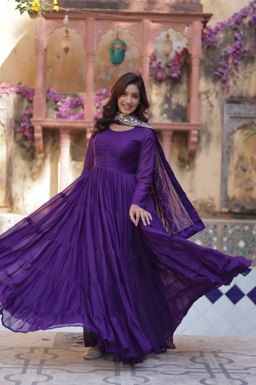 Woman in a flowing purple flared gown and embroidered dupatta, twirling gracefully.