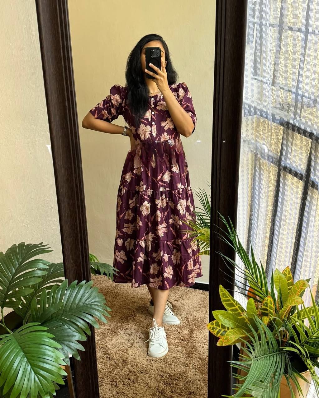 Full-length view of a woman wearing the plum floral Moringa Maxi dress with white sneakers.