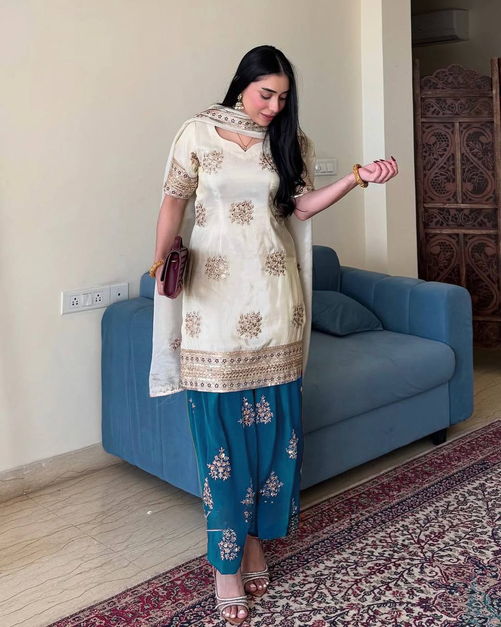 Woman in cream and teal Rangbhoomi party wear, showcasing silk fabric and embroidery details.