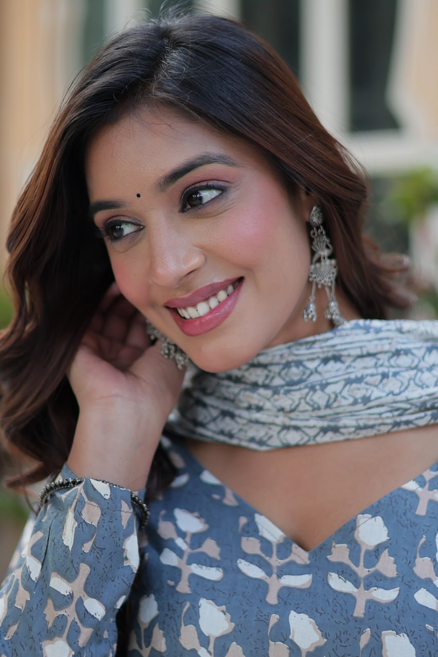 Smiling woman in a blue kurti set, close-up on soft cotton fabric and traditional silver earrings.