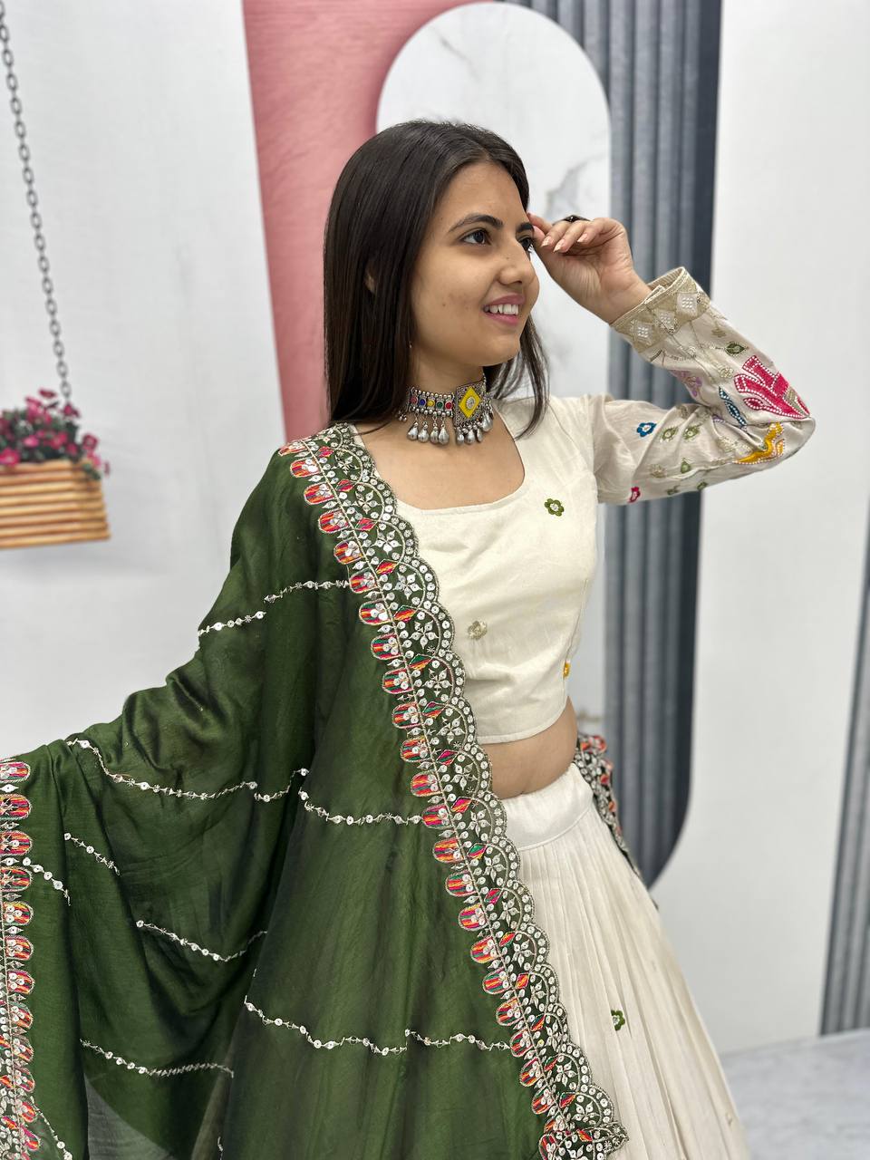 Woman smiling in an off-white lehenga choli with an olive green dupatta.