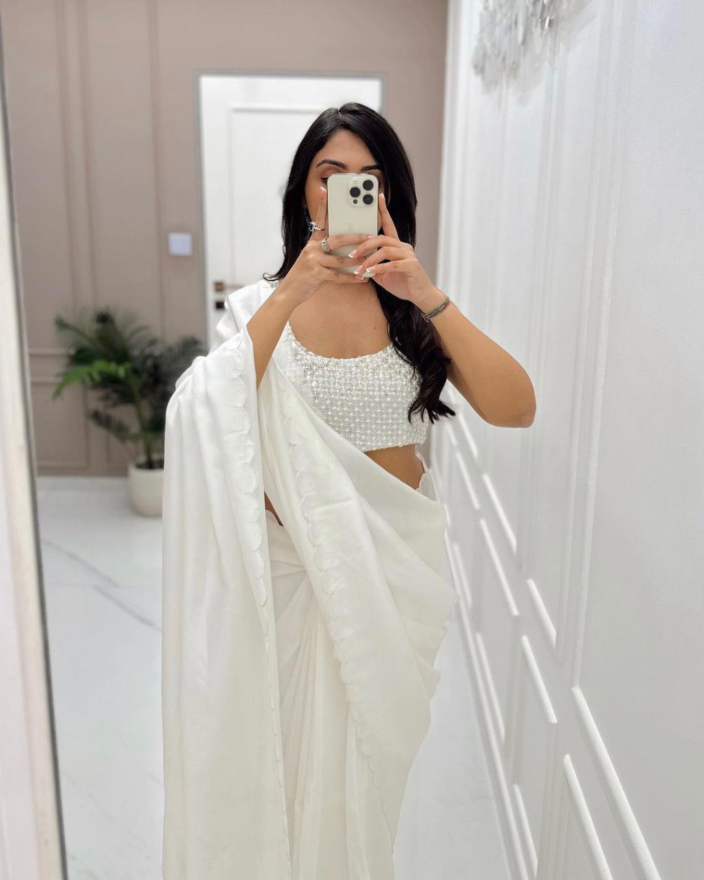 Woman taking selfie in ready to wear white saree and beaded blouse outfit.