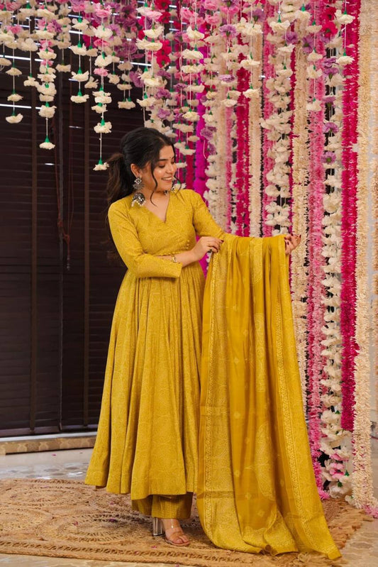 Woman in Golden Bandhani Anarkali Suit Set holding dupatta. Ethnic dress.