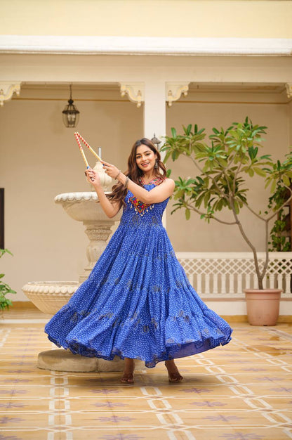 Woman in blue Bandhani gown striking a pose with dandiya sticks for Garba night.