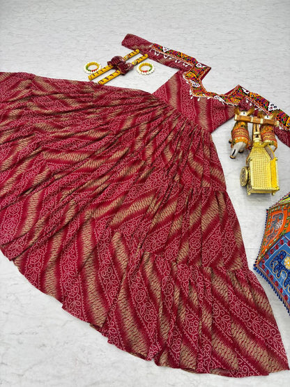 Red Bandhni Gamathi work gown laid flat, paired with dandiya sticks and festive accessories.