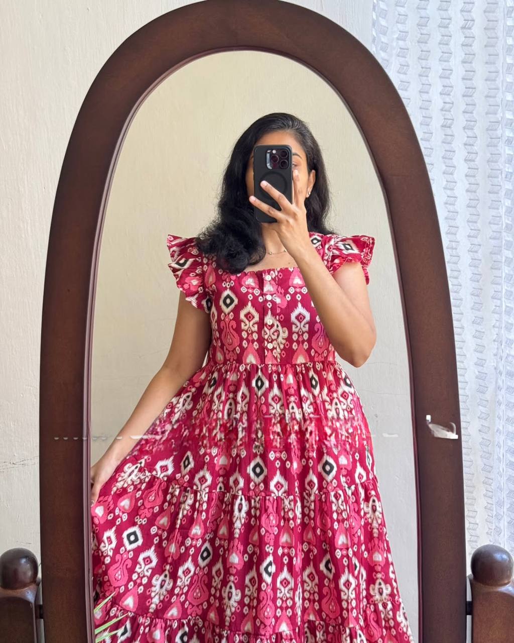 Close-up mirror shot of woman in Dhano Maxi pink Patola dress.