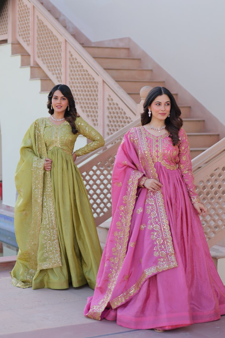 Two women in traditional green and pink dresses standing on a staircase.