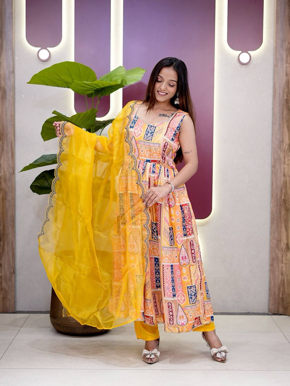 Woman posing in vibrant yellow printed Anarkali suit with dupatta.