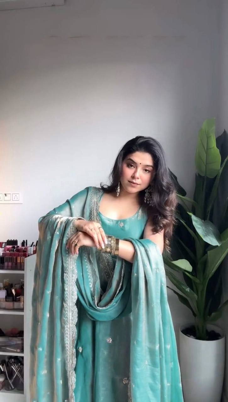 Woman in elegant teal gown ensemble with dupatta.
