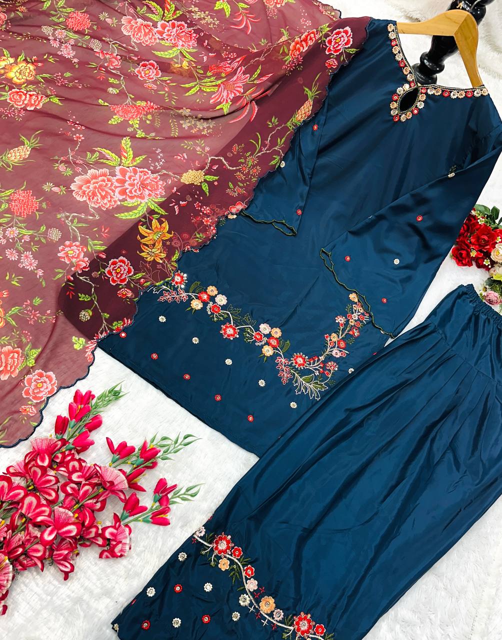 Flat lay of navy blue Farsi salwar kameez set with floral embroidery and maroon dupatta.