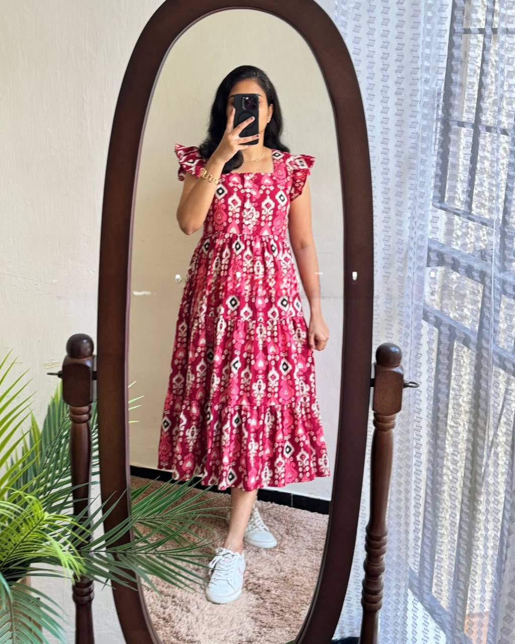 Woman in mirror wearing Dhano Maxi pink Patola print dress and white sneakers.