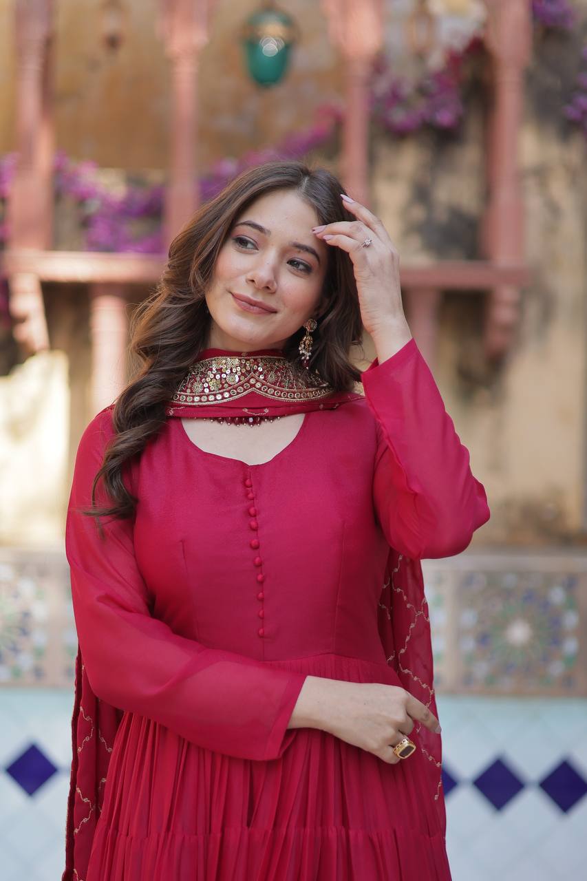 Woman wearing a red flared gown with embroidered dupatta, looking off to the side.
