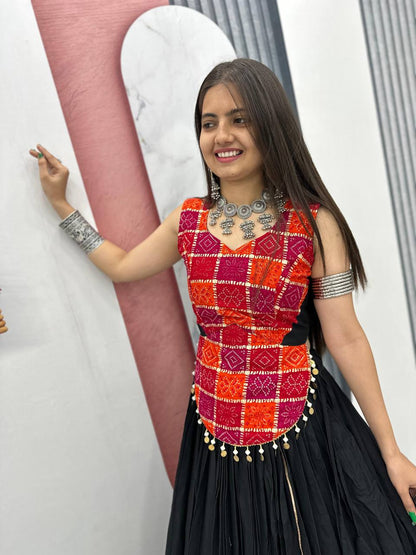 Happy woman modeling traditional vibrant choli and black lehenga, showcasing jewelry and festive look.