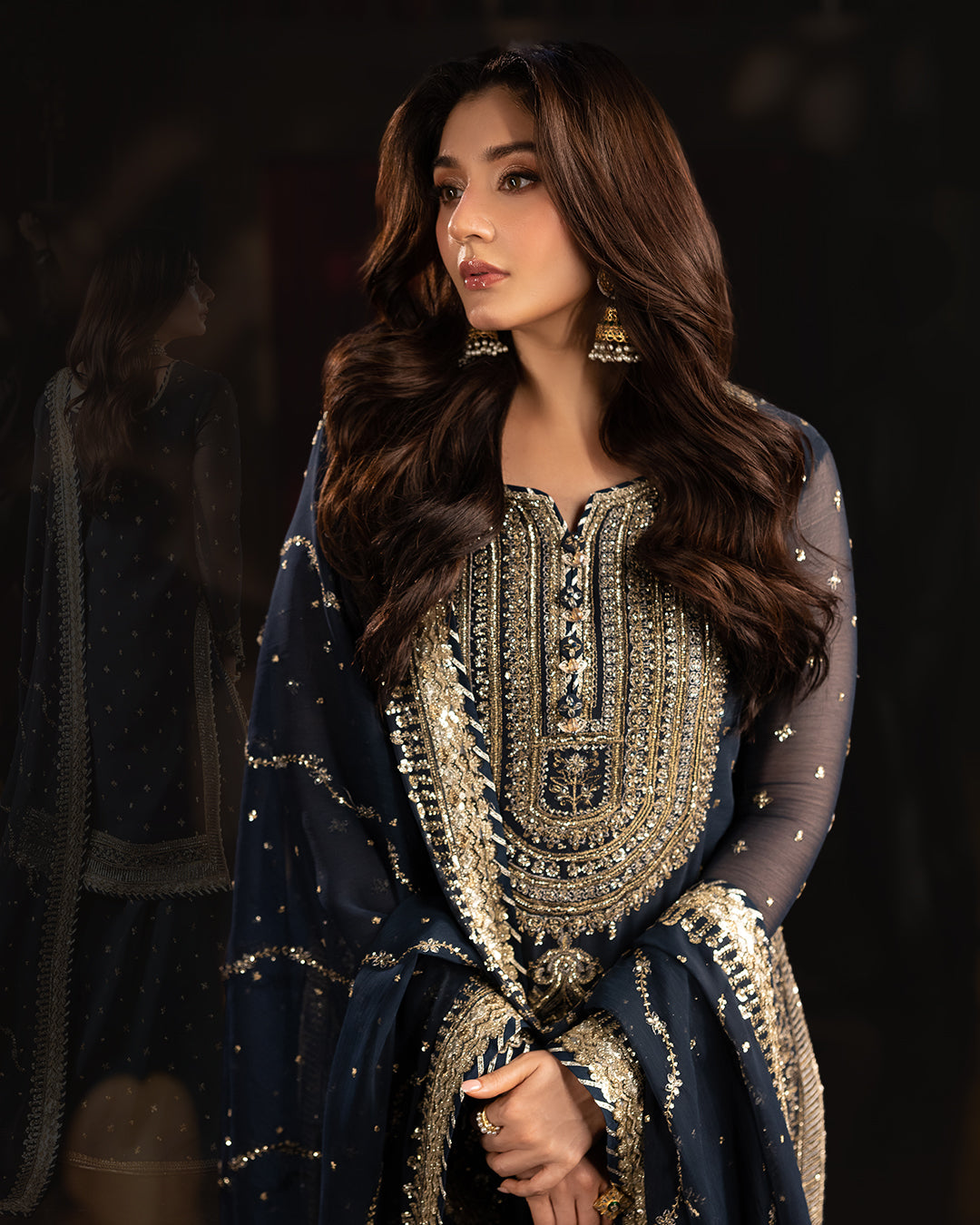 Model in navy blue sharara set with detailed gold embroidery and dupatta, styled for festive occasions.