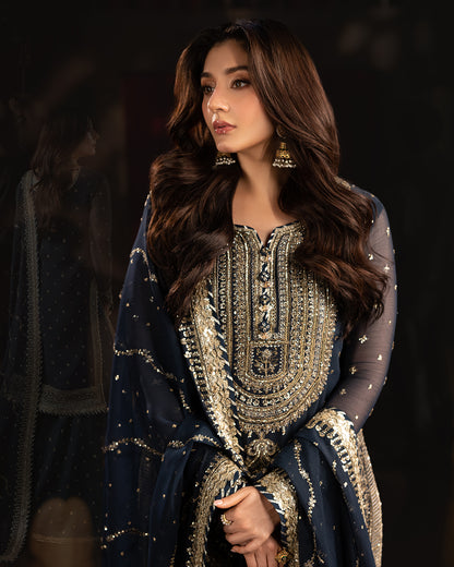 Model in navy blue sharara set with detailed gold embroidery and dupatta, styled for festive occasions.
