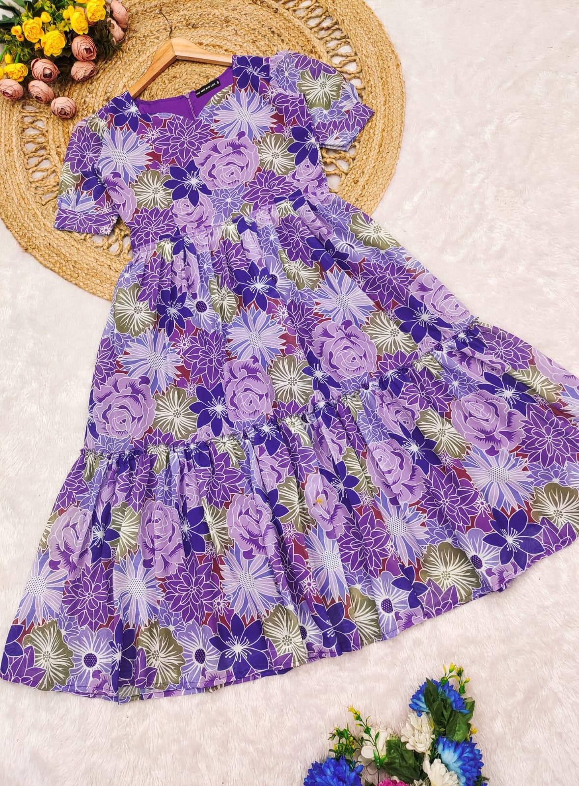 Woman posing in a purple floral V-neck maxi dress with tiered design.