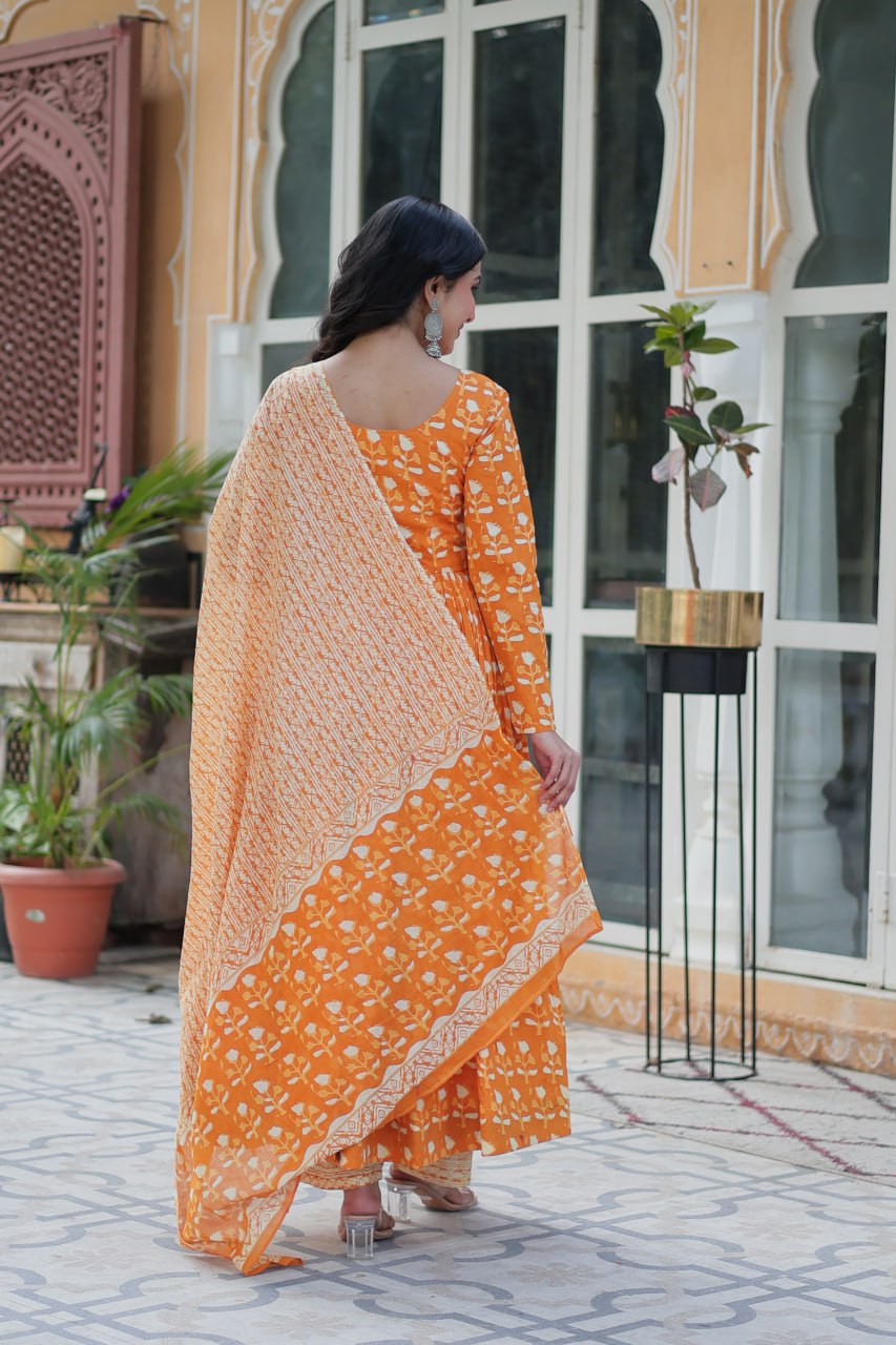 Woman in orange floral kurti set, holding soft dupatta, styled for comfort and everyday elegance.