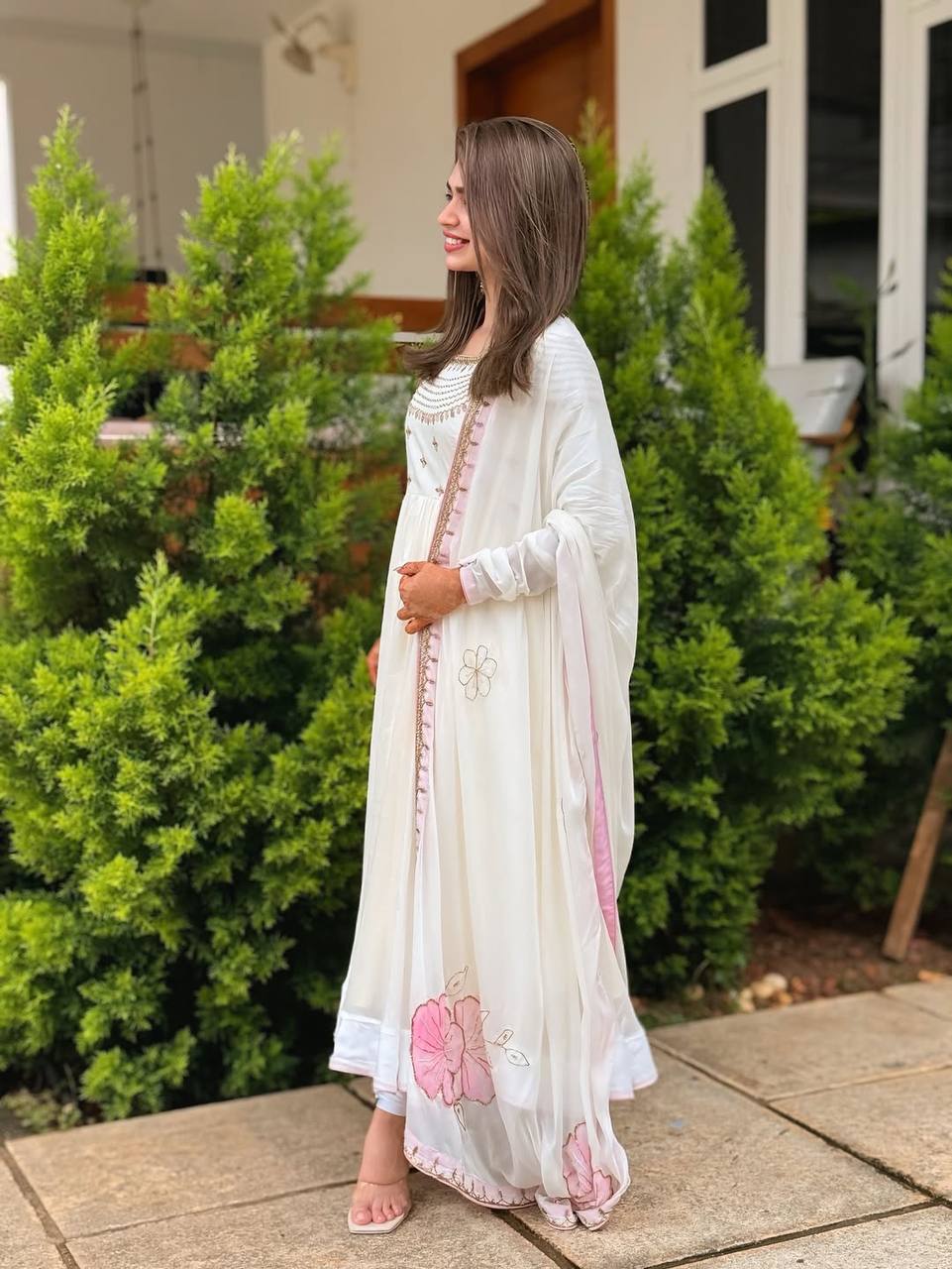 Side view of model in embroidered glam off-white gown with pastel pink floral dupatta.