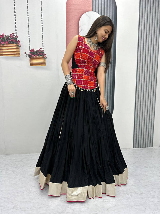 Model in swirling black lehenga and red foil print choli, showing off elegant festive Navratri attire.