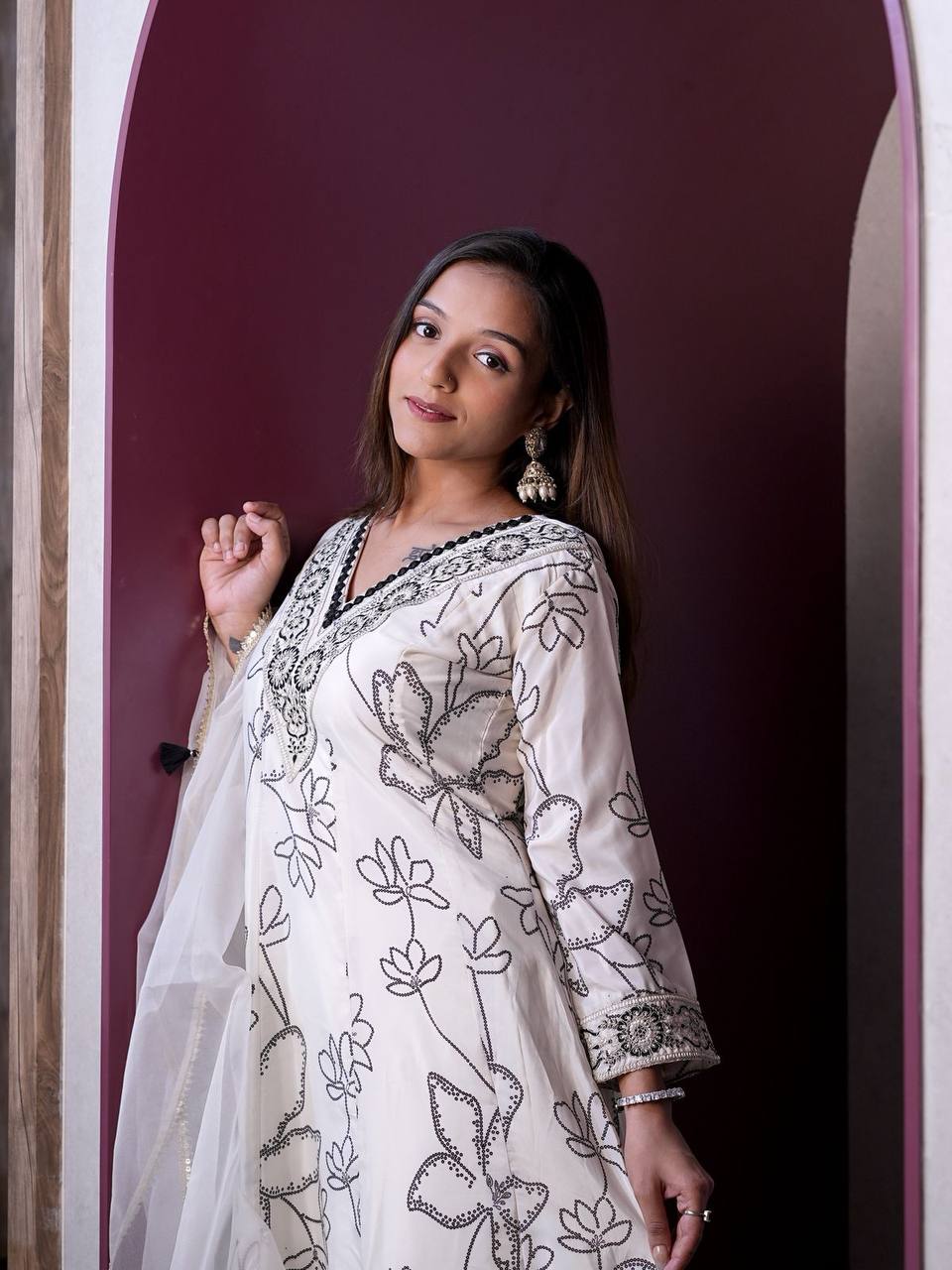 Woman in white Anarkali suit with digital print and organza dupatta, full-length view.
