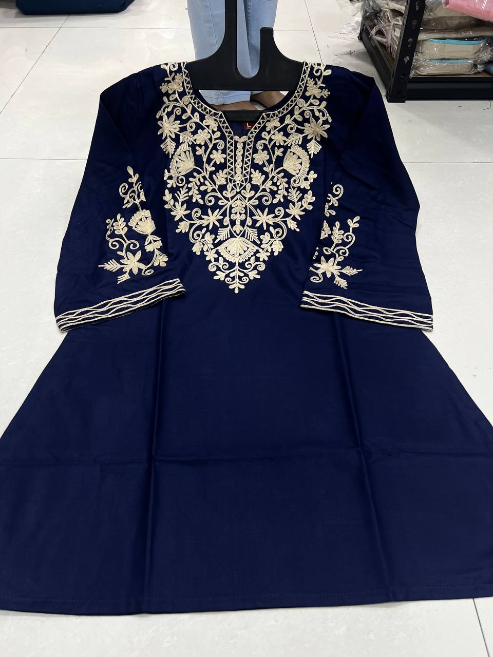Adaa ShortKurti in deep blue displayed on a hanger, showcasing intricate floral embroidery on the front.