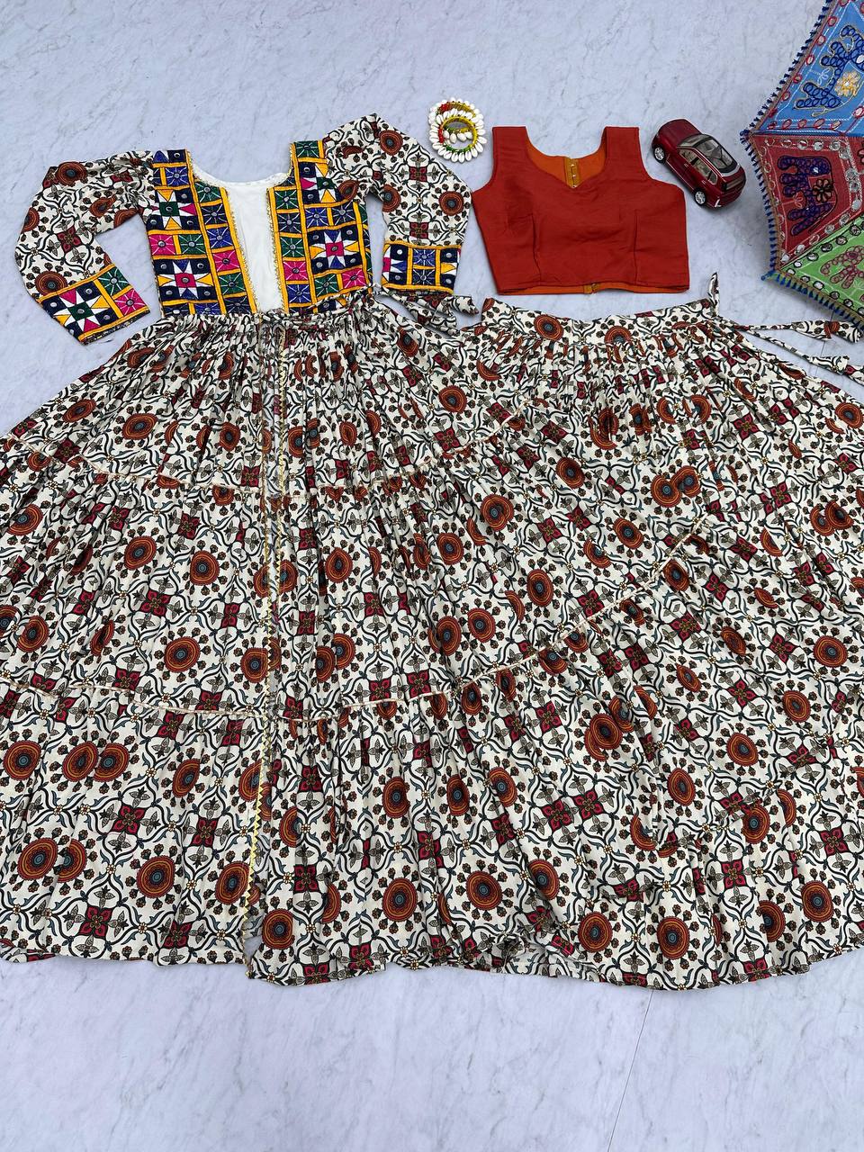 Flat lay of full Kachchi Charm lehenga choli set with embroidered shrug, orange blouse, and flared skirt.