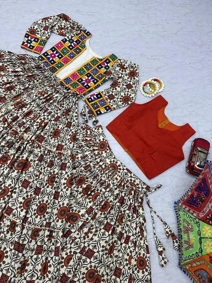 Flat lay of lehenga choli set, featuring mirror work shrug, orange blouse, and traditional festive skirt.