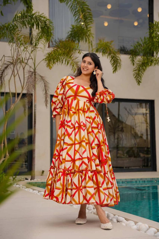 Woman in Sajda Maxi Dress in red-orange-white geometric print near a pool.