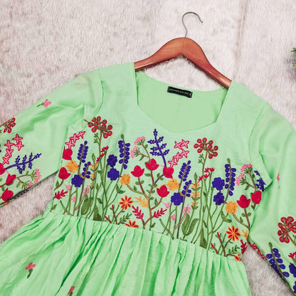 Close-up of the light green dress embroidery and Maska cotton fabric texture.