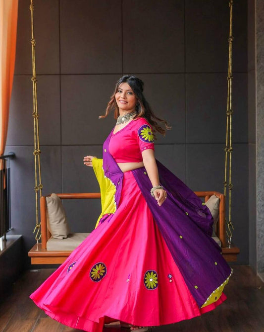 Smiling woman twirling in vibrant pink lehenga with floral embroidery and purple-yellow dupatta, Navratri style.