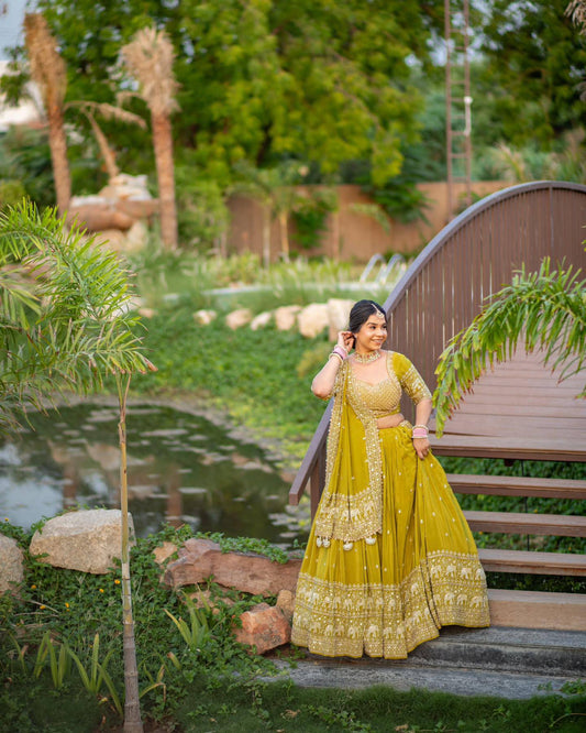 Woman in a lime green embroidered lehenga choli posing on a bridge.