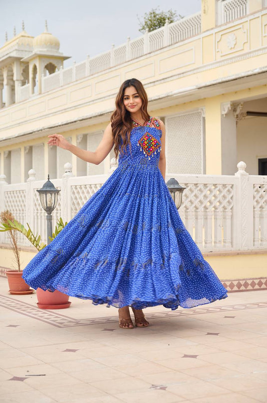 Woman twirling in royal blue Bandhani Gamathi work gown with mirror embroidery, outdoors.
