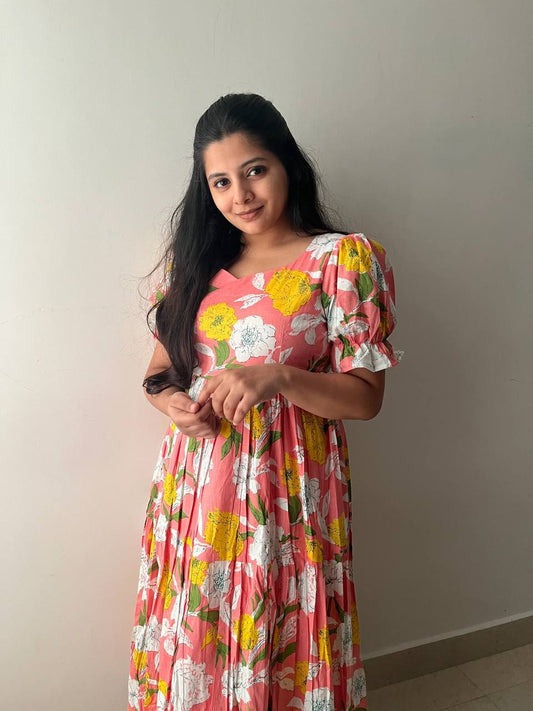 Woman wearing a pink floral maxi dress with yellow and white flowers.