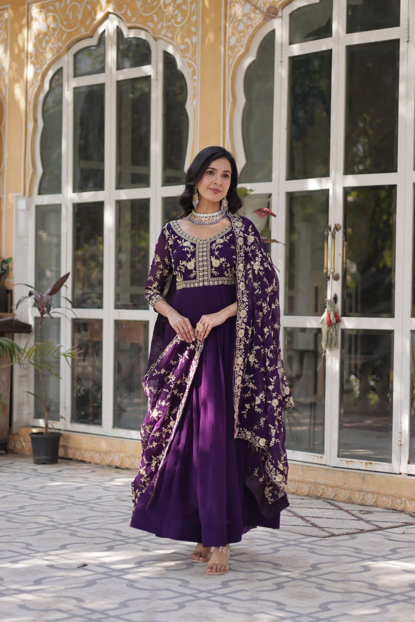 Model twirling in purple embroidered Indian gown with dupatta.