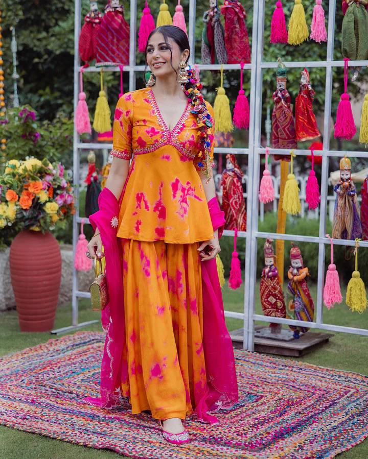 Woman wearing an orange and pink printed palazzo set with a matching dupatta.