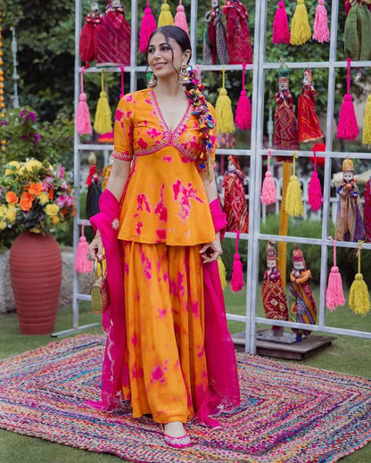 Woman wearing an orange and pink printed palazzo set with a matching dupatta.