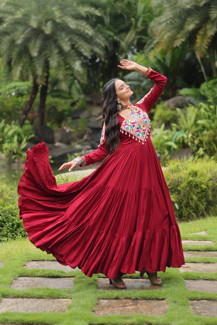 Elegant maroon Gamthi Gown with colorful embroidery, voluminous skirt, and joyful Navratri dance pose.
