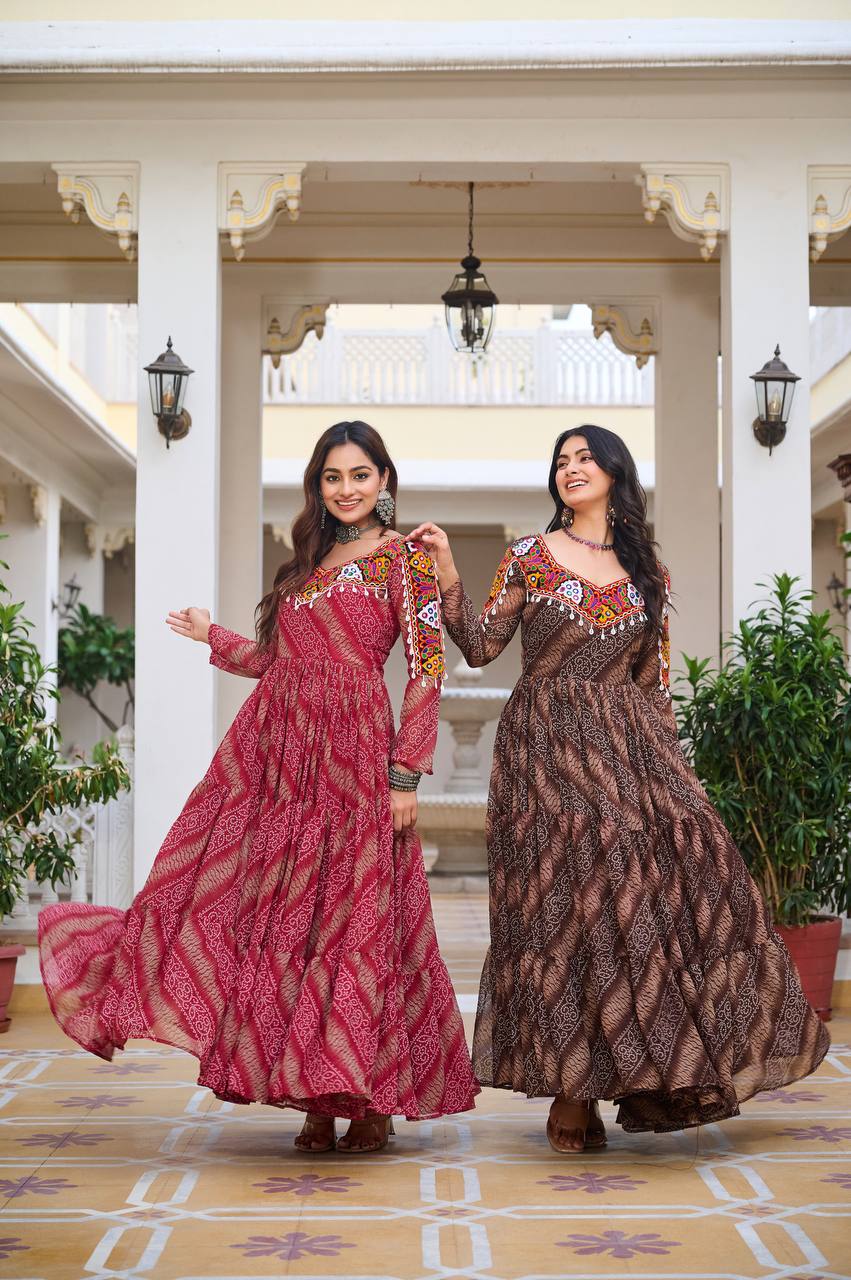 Two women in red and brown Bandhni Gamathi gowns, twirling together for Navratri celebrations.