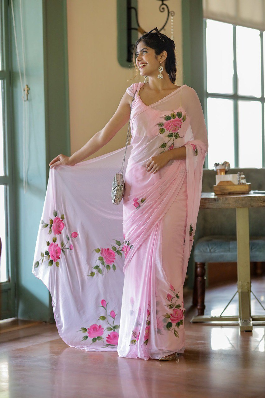Model smiling in pink rose georgette saree with silver purse.